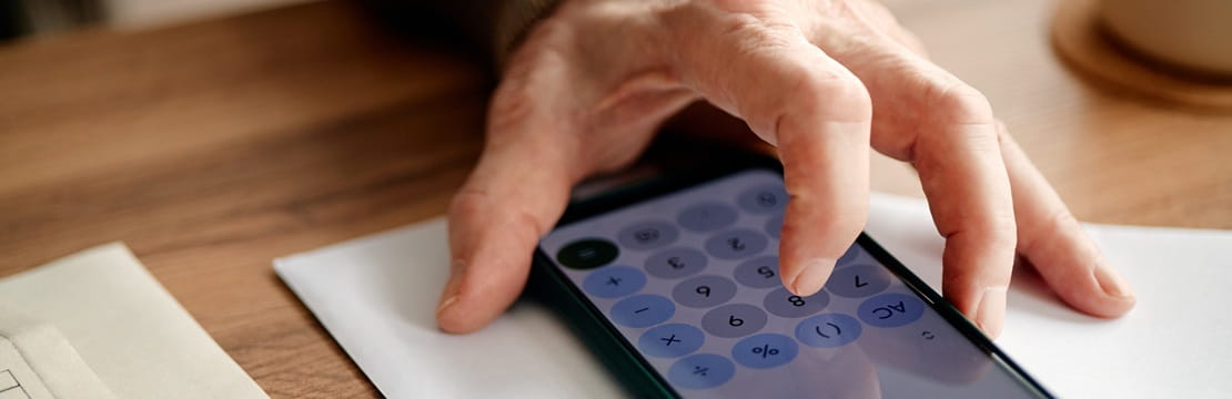 Close-up of a person using a calculator on a smartphone, symbolizing retirement income planning and evaluating how the 2027 Social Security cost-of-living adjustment may affect future benefits and retirement strategies.