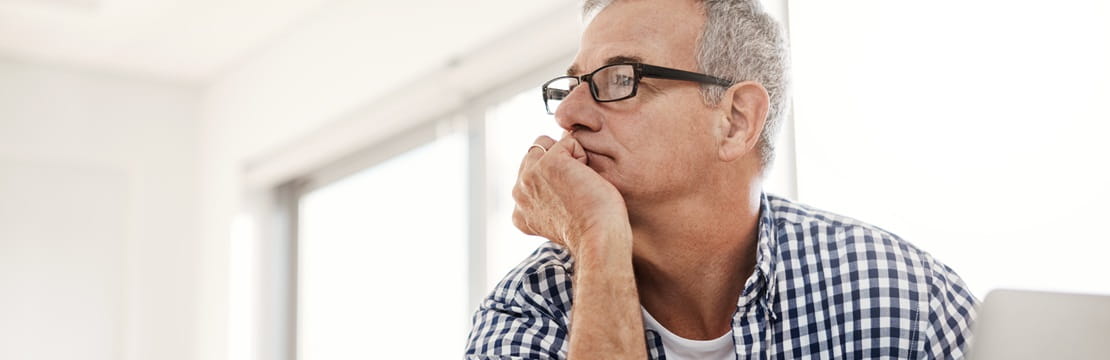 hot of a mature man looking thoughtful while working on a laptop at home